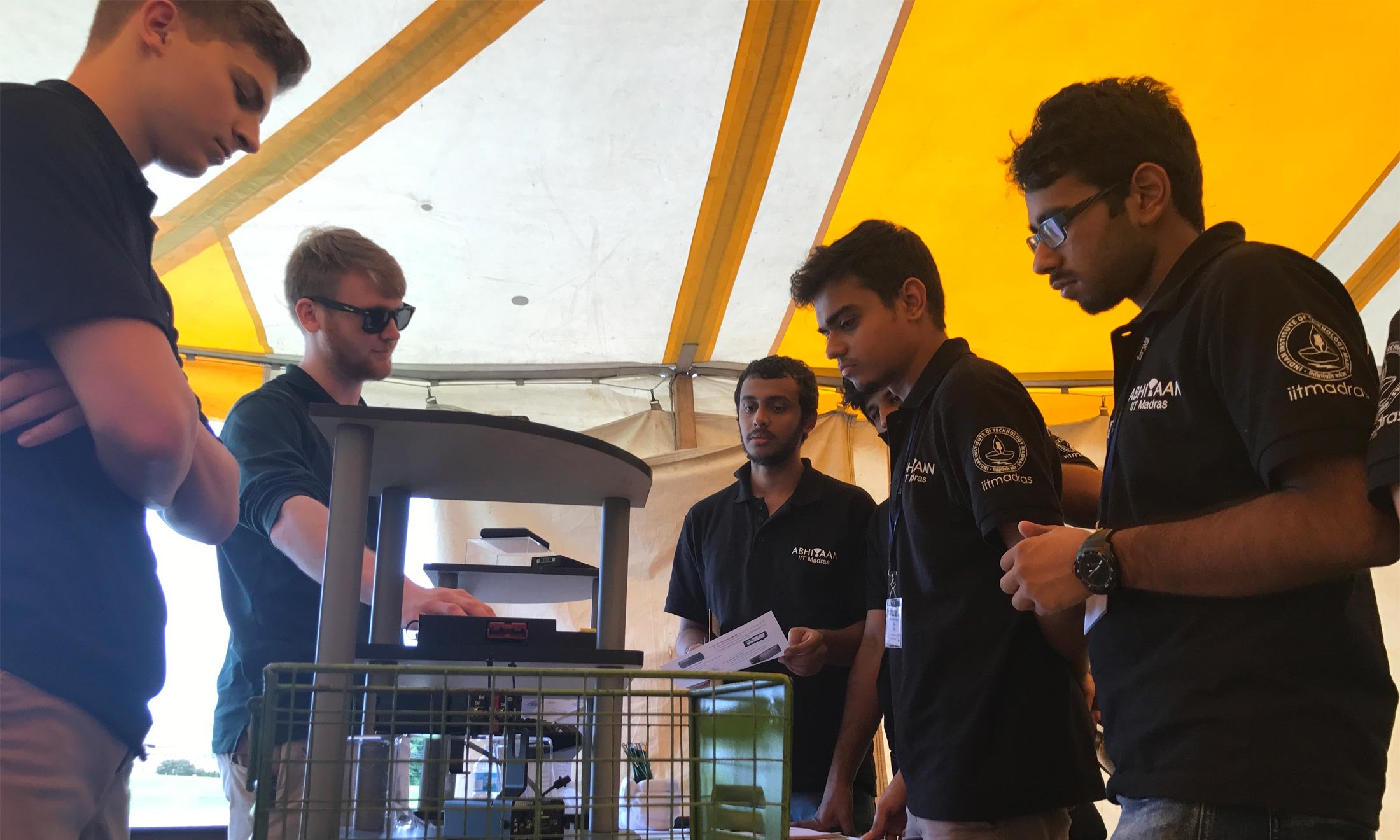 Students discuss their projects for the IGVC competition at Oakland University under a yellow tent