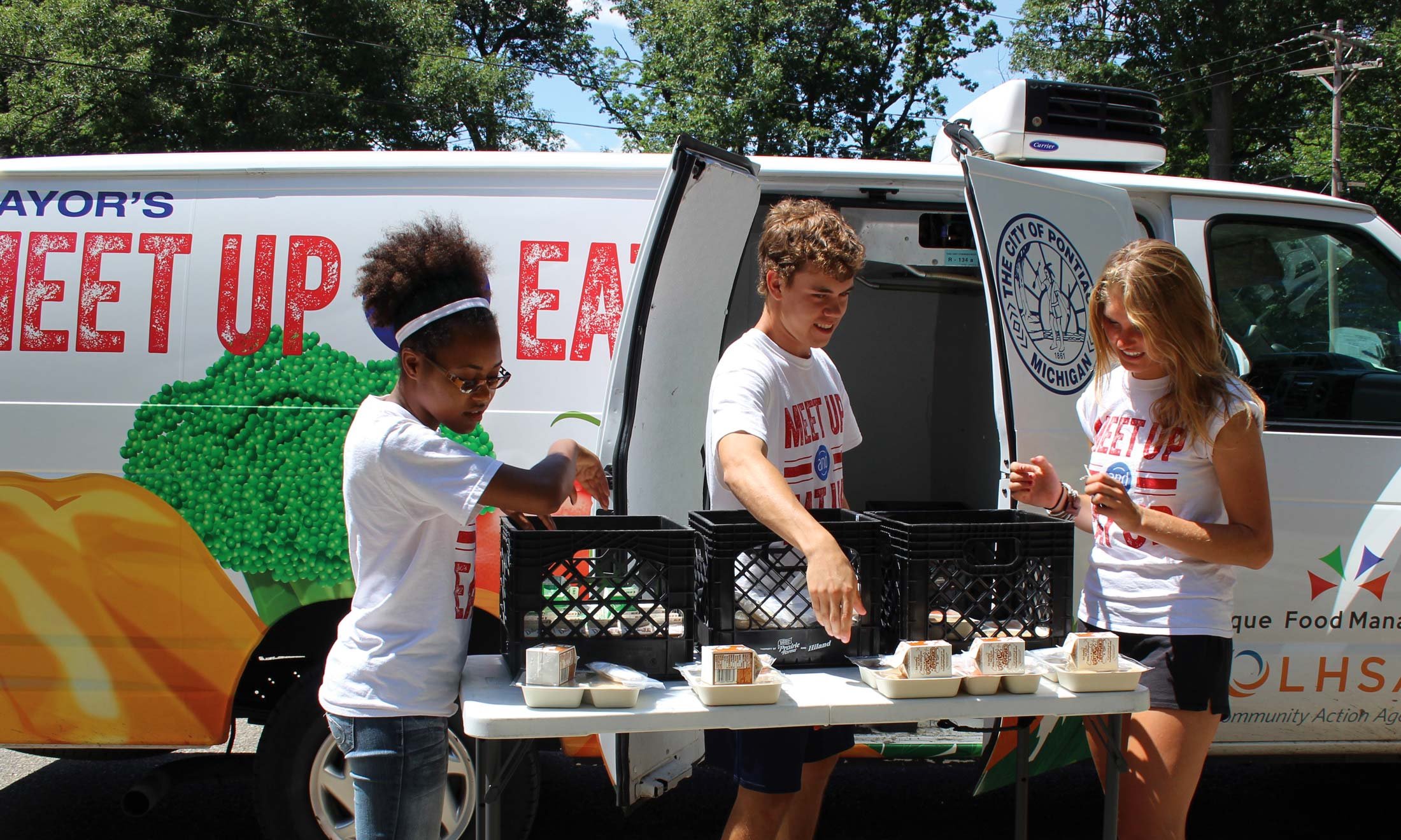 The Healthy Pontiac, We Can! Initiative staff sets food on a table at a pop-up produce market in Pontiac, MI