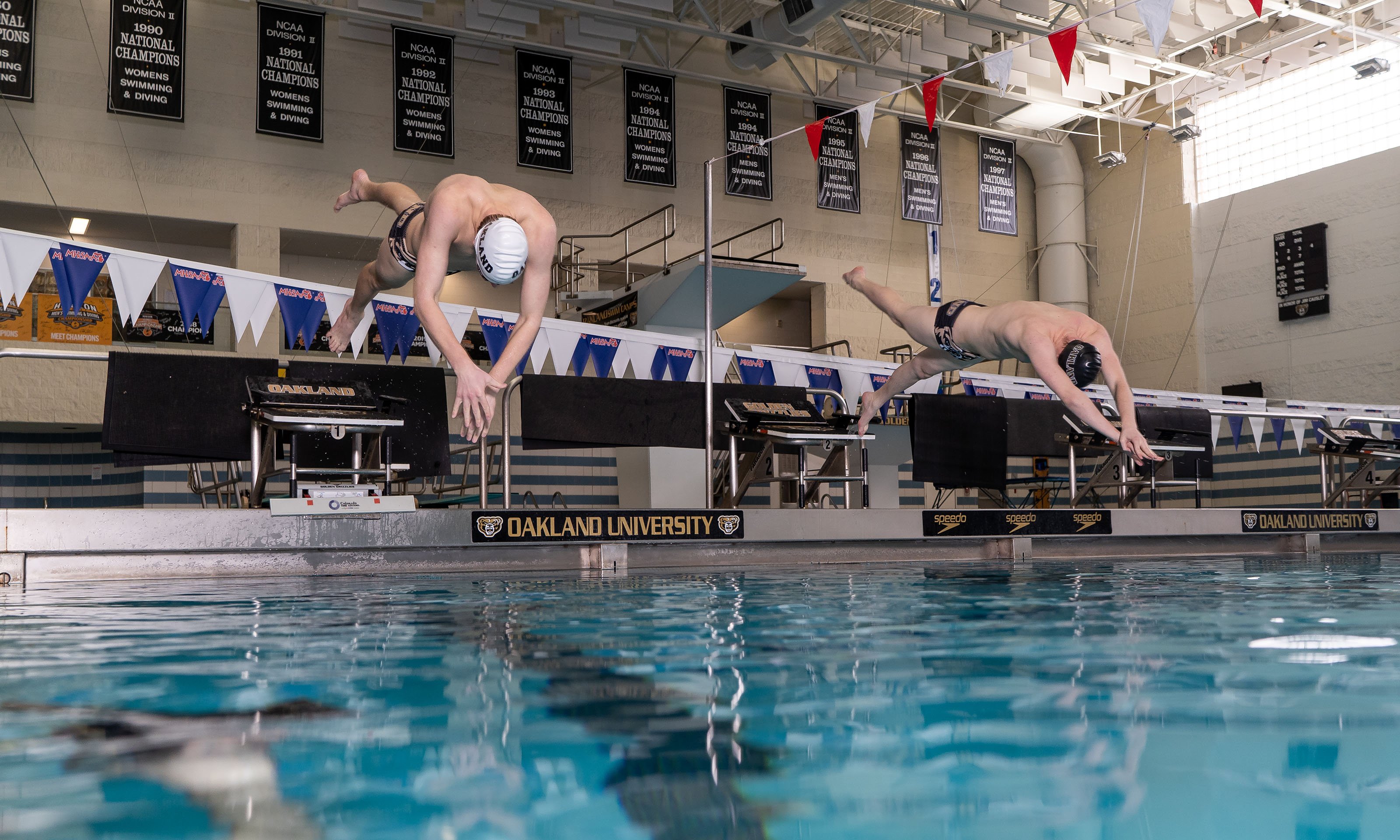 two male swimmer jumping into water