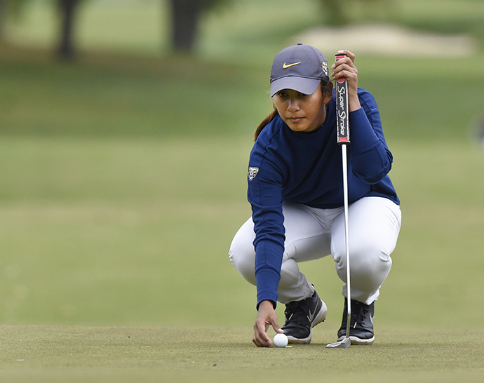 A woman kneeling with a golf club.