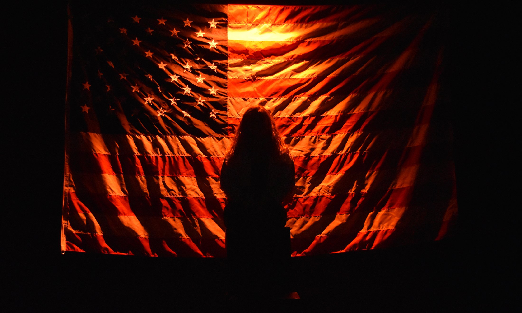 A silhouette of a person in front of the USA flag.