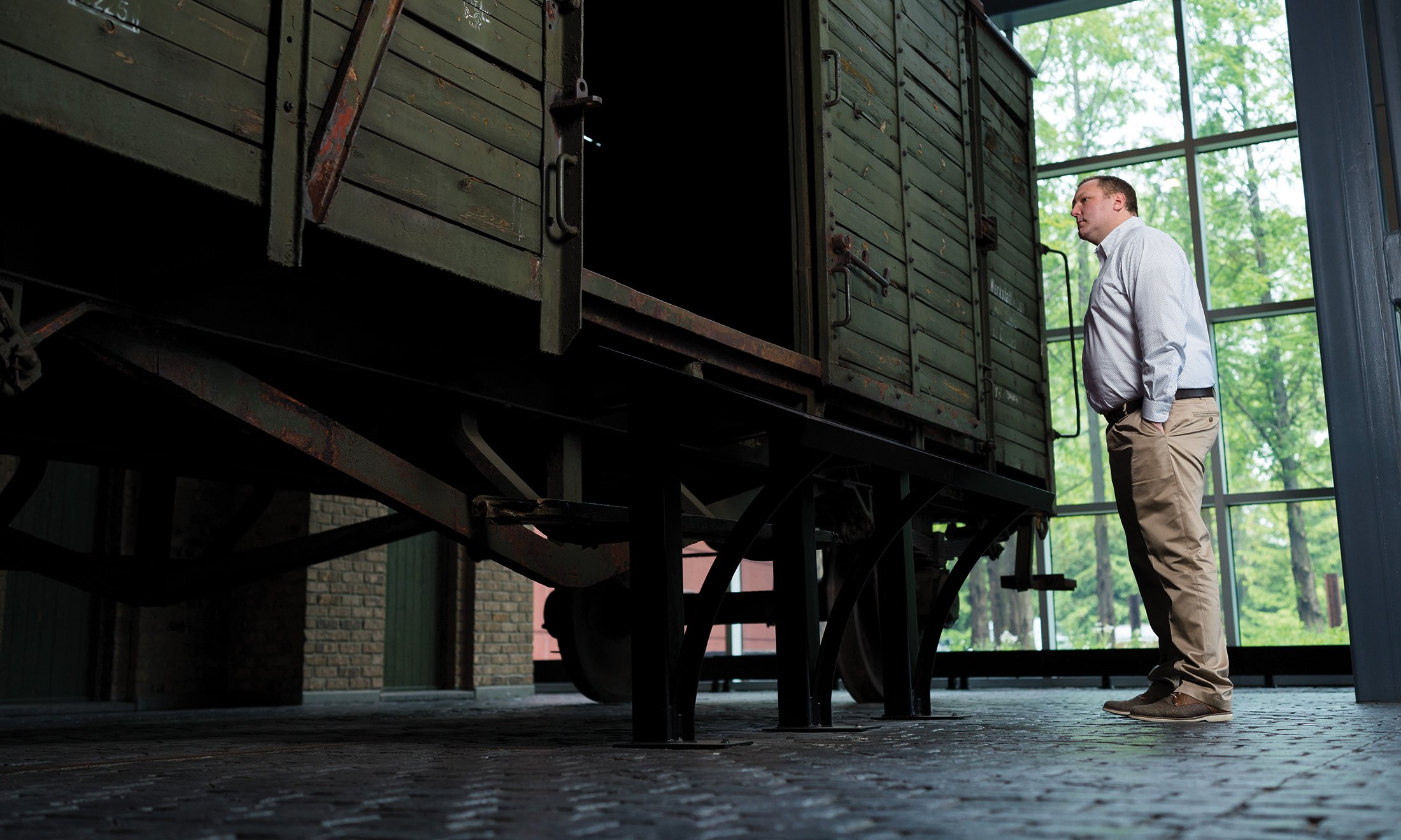 A man looking at a train car at a Holocaust ecxhibit.