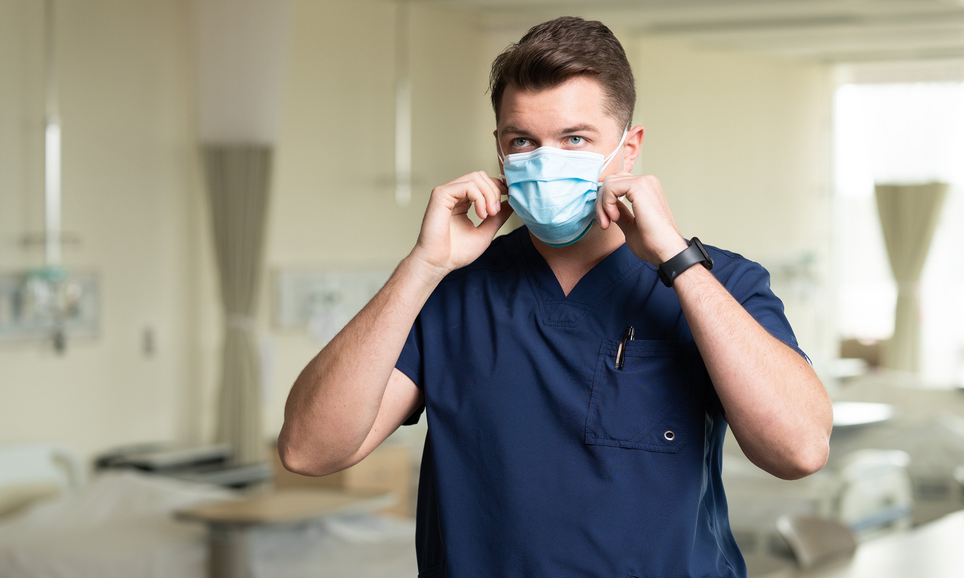 A man wearing a N95 putting a surgical mask overtop.