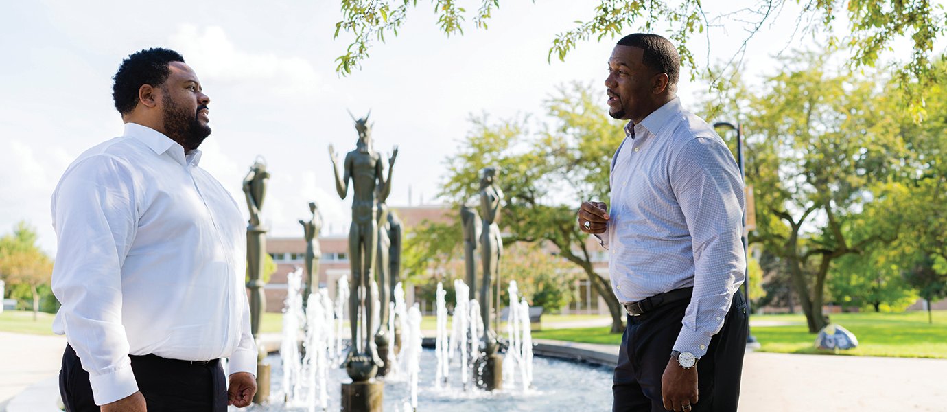 Two man standing in front of a fountain on Oakland University's campus.