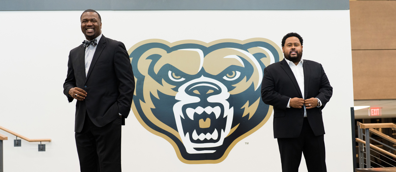 Two men standing in front of Grizz Bear logo