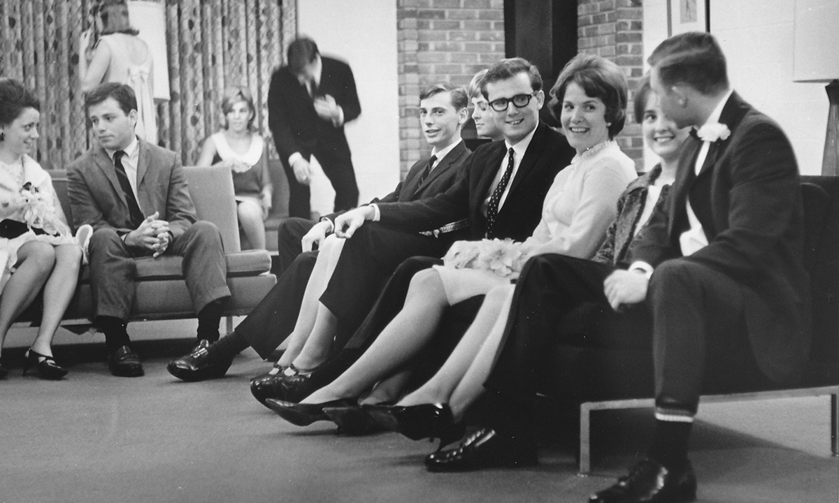 A group of people in traditional 1960's clothing sitting on a couch