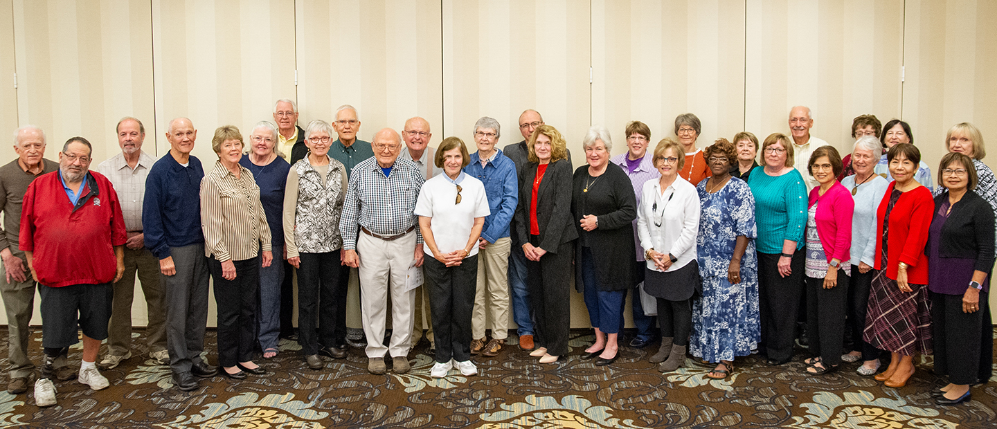 Large group of senior citizens standing in a banquet room, posing for a photo.