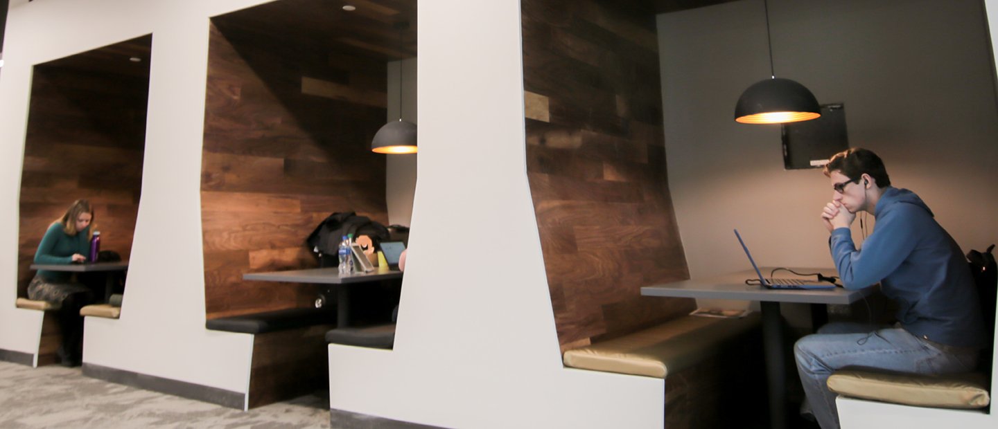 Application Preparation Students sitting at benches set into the wall in a common space at Oakland University.