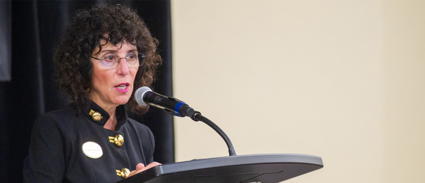 President Ora Hirsch Pescovitz speaking into a microphone on a podium