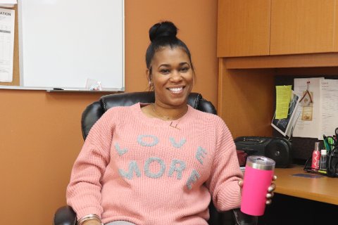 Farrah Adams, seated at a desk, smiling at the camera.