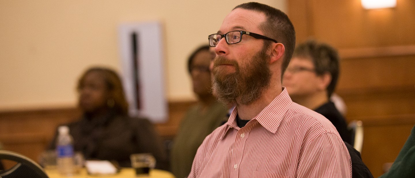 Evolutionary Psychology Interdisciplinary Conference Series A man seated in a row of people at a conference.