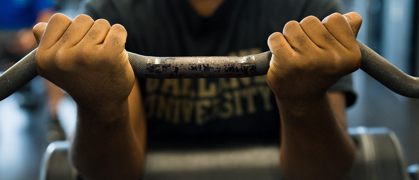 A person holding a barbell with an underhand grip.