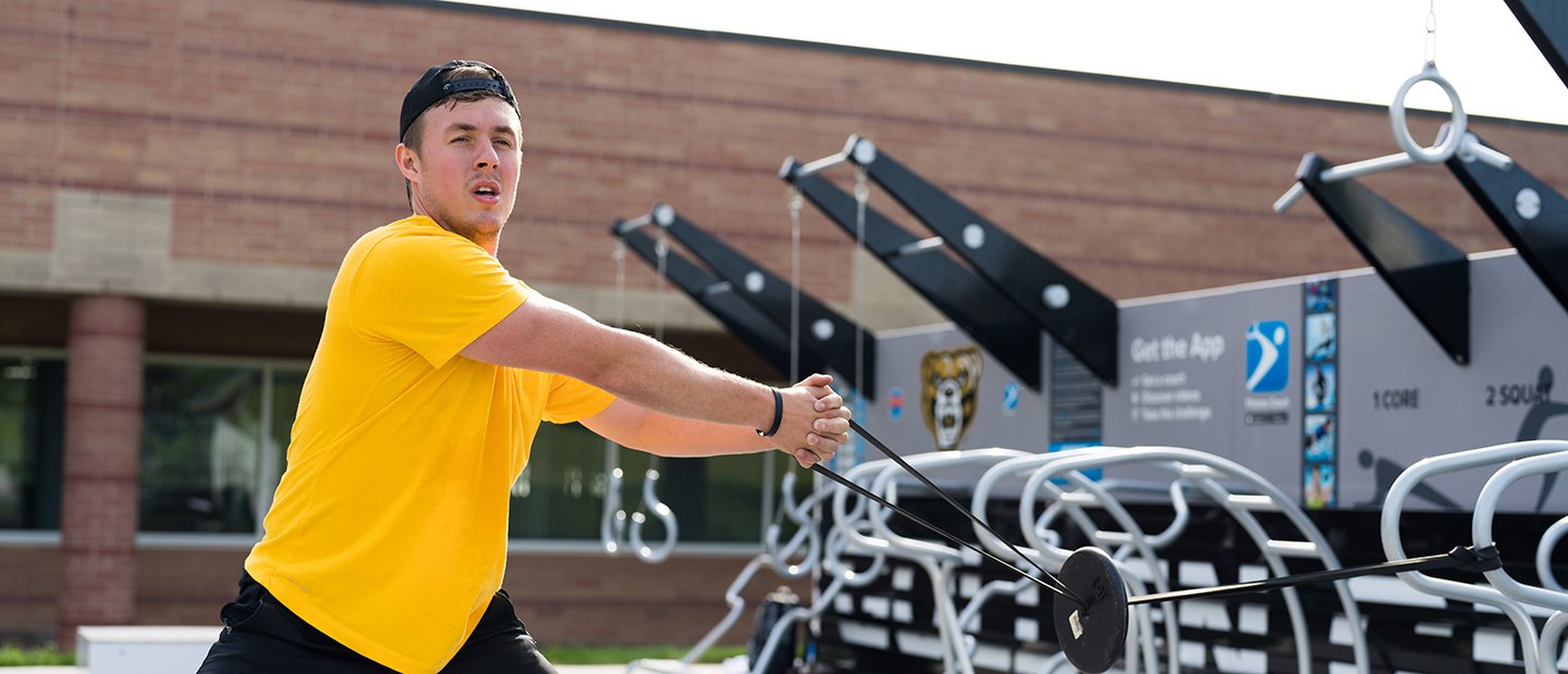 A man working out with a resistance band at the outdoor Fitness Court.