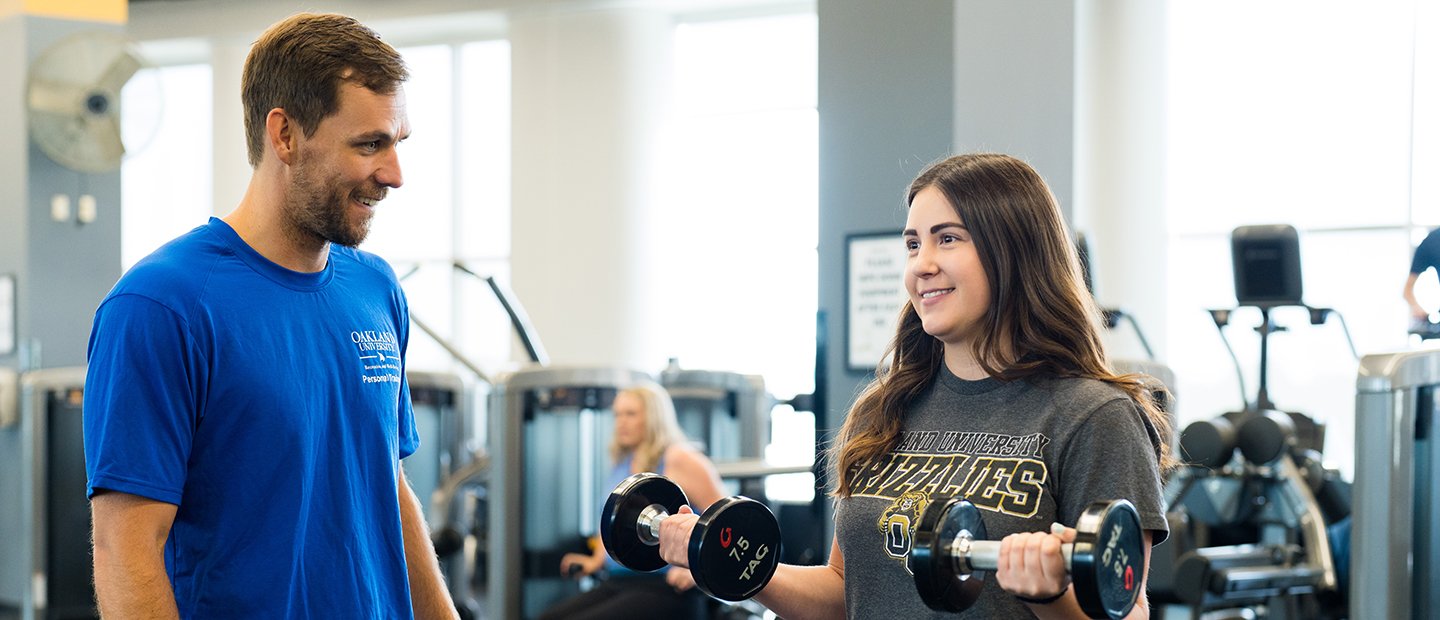 A personal trainer instructing a gym member who is doing bicep curls.