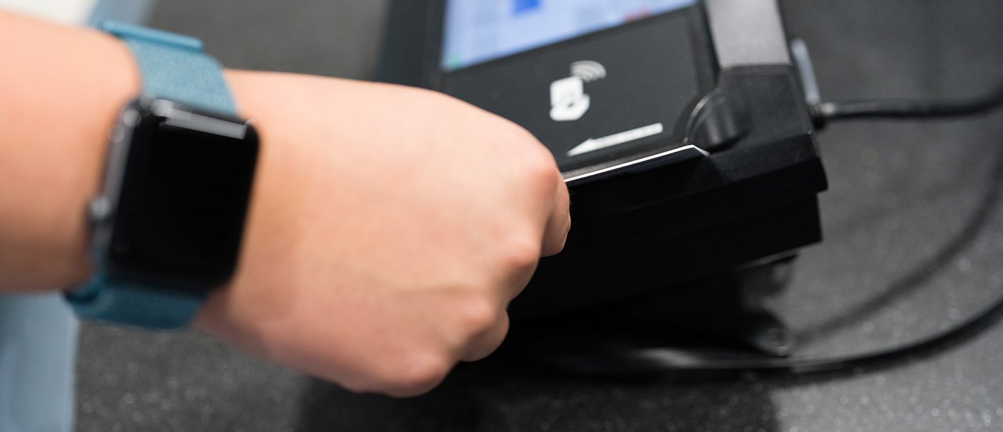 A hand swiping a card through a card reader.