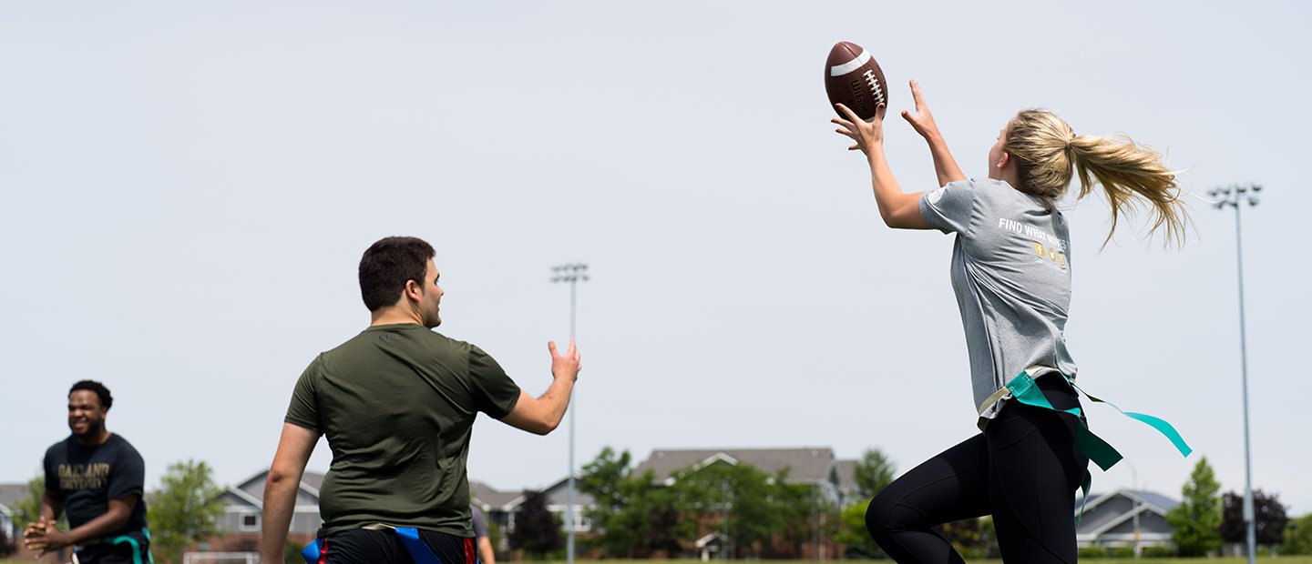 A woman catching a football in a flag football game.