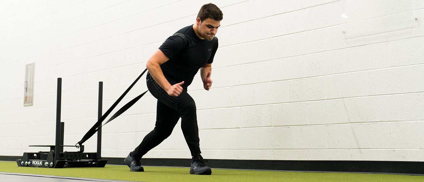 A man pulling a weight sled in the recreation center.