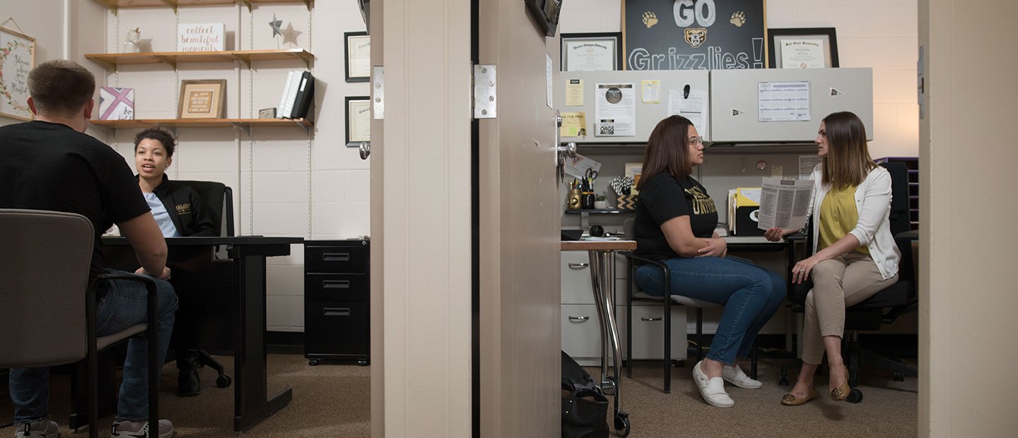 Two offices with the doors open, showing a student talking to a staff member in each office.