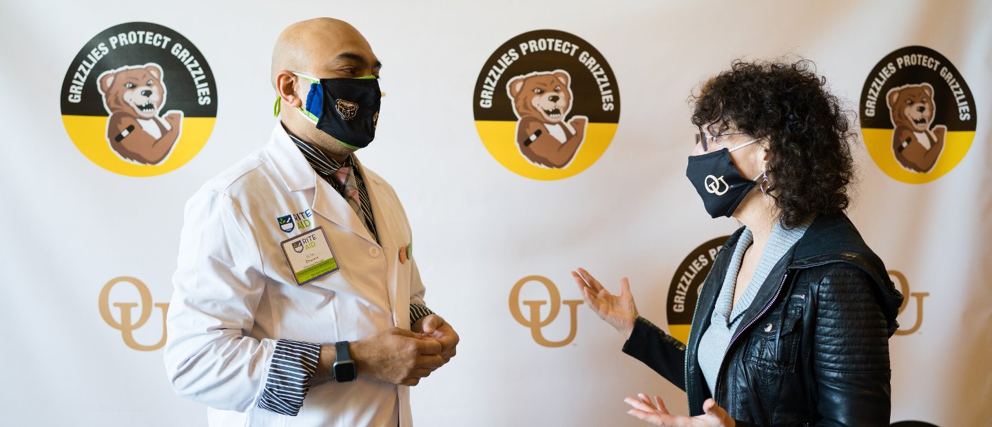President Pescovitz speaking with a doctor in a white lab coat, both wearing masks.