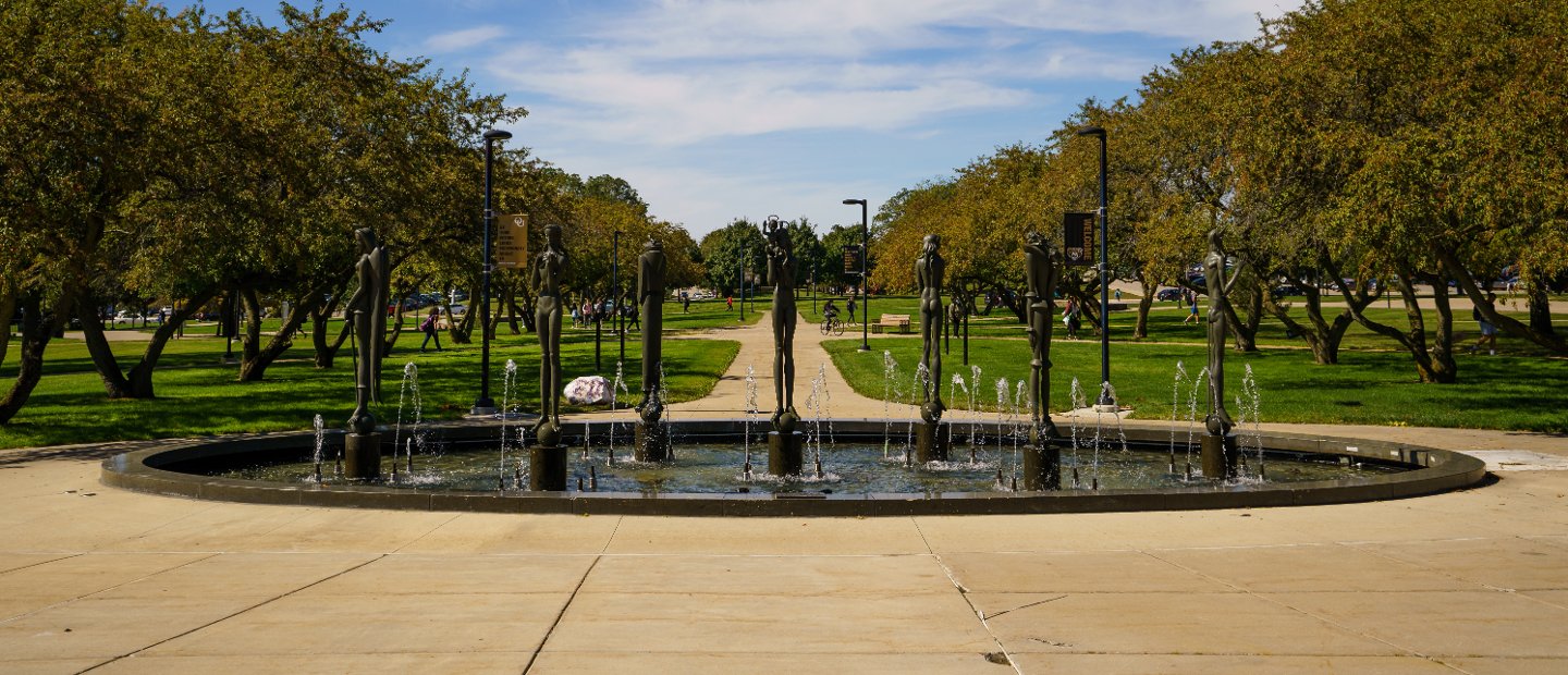 A fountain with bronze statues surrounding it on Oakland University's campus.