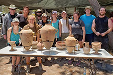 Students and faculty group standing in front of archaeological artifacts