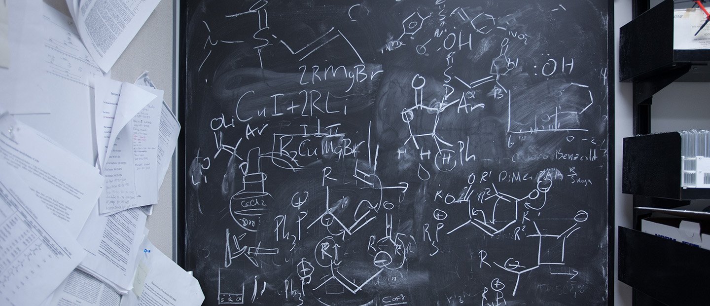 A chalkboard with chemical equations and diagrams written on it.