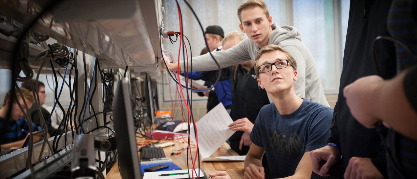 students in a lab with electronic devices with many red and black cables