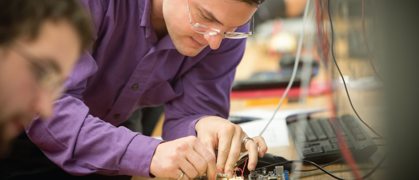 two students working on a small circuit board