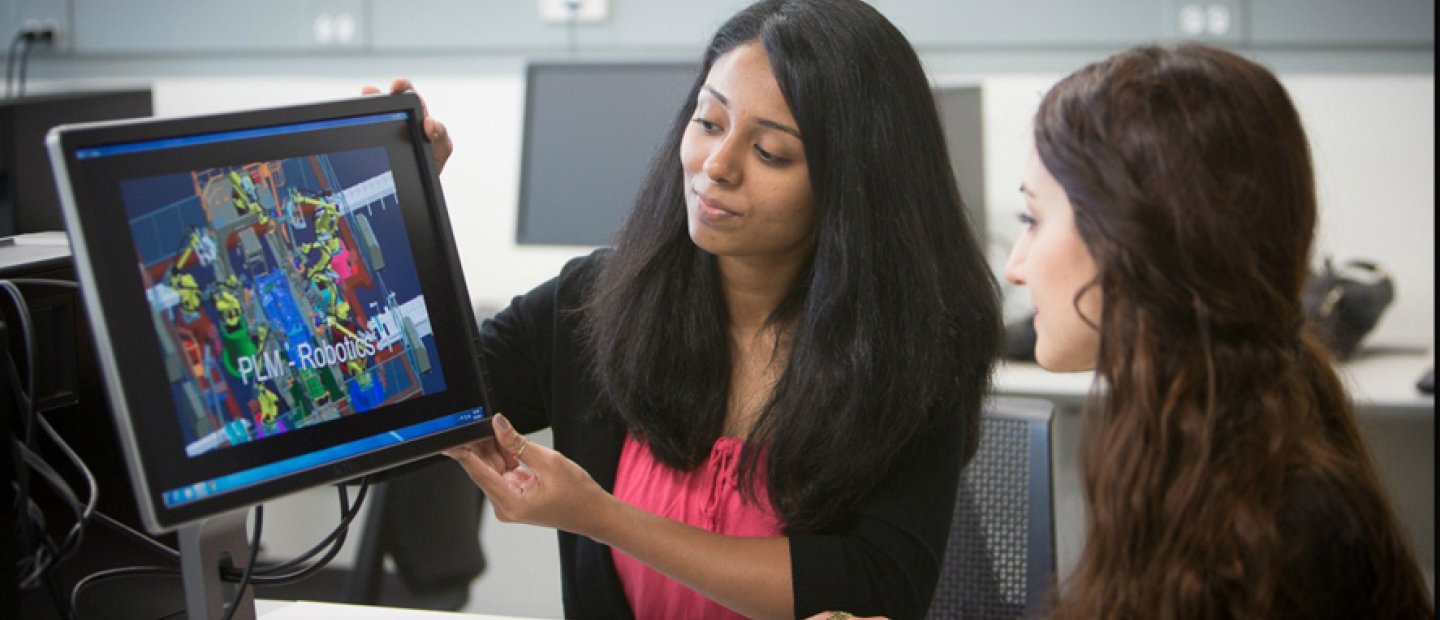 Industrial and Systems Engineering woman showing a screen with colorful images and P L M - Robotics on it to a student