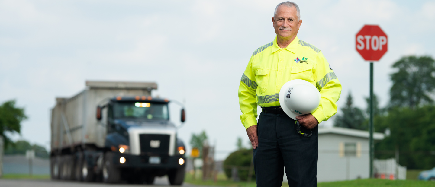 A safety manager standing in front of a truck, smiling at the camera.