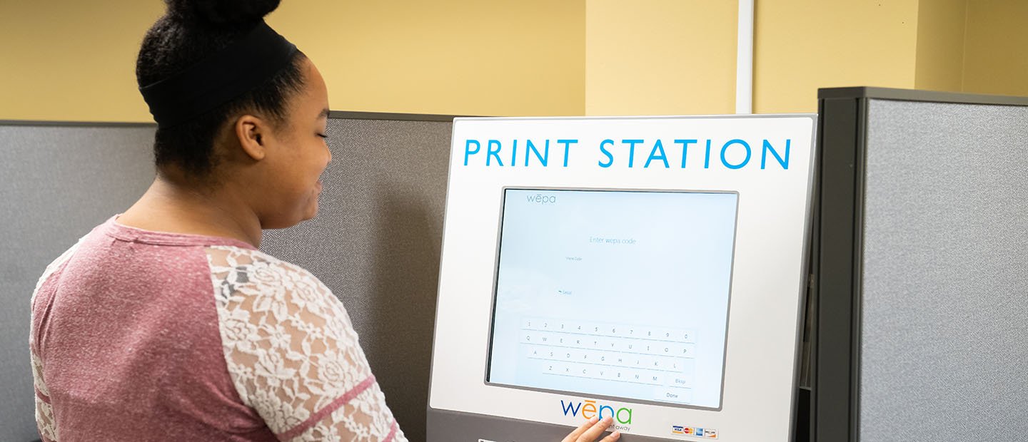young woman standing at a computer screen on a Print Station 