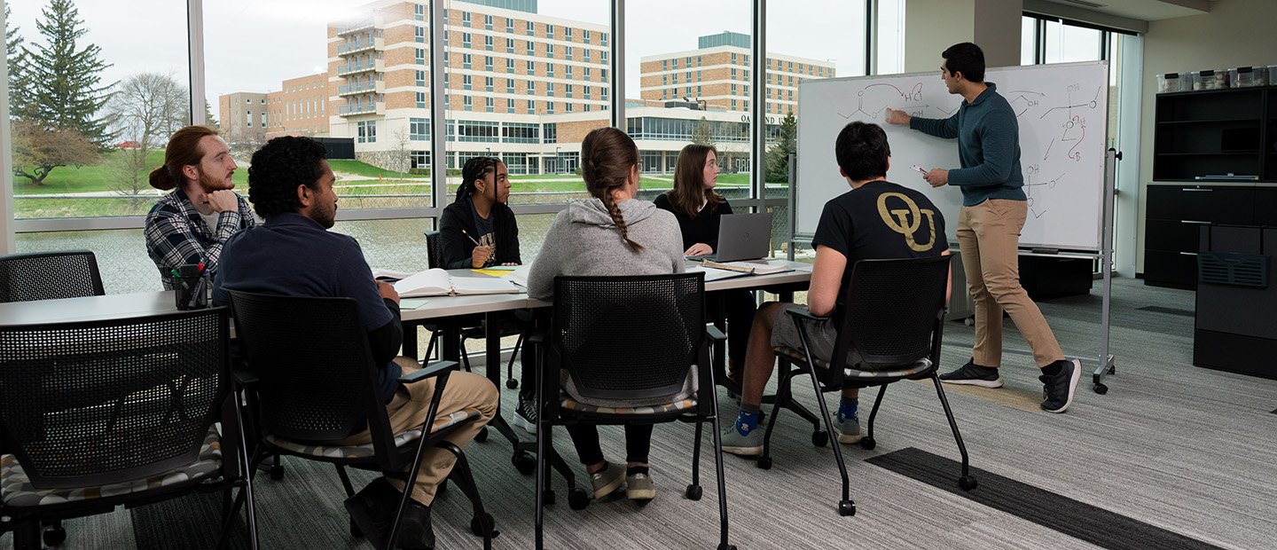 Supplemental Instruction A group of students seated while a man explains something drawn on a white board.