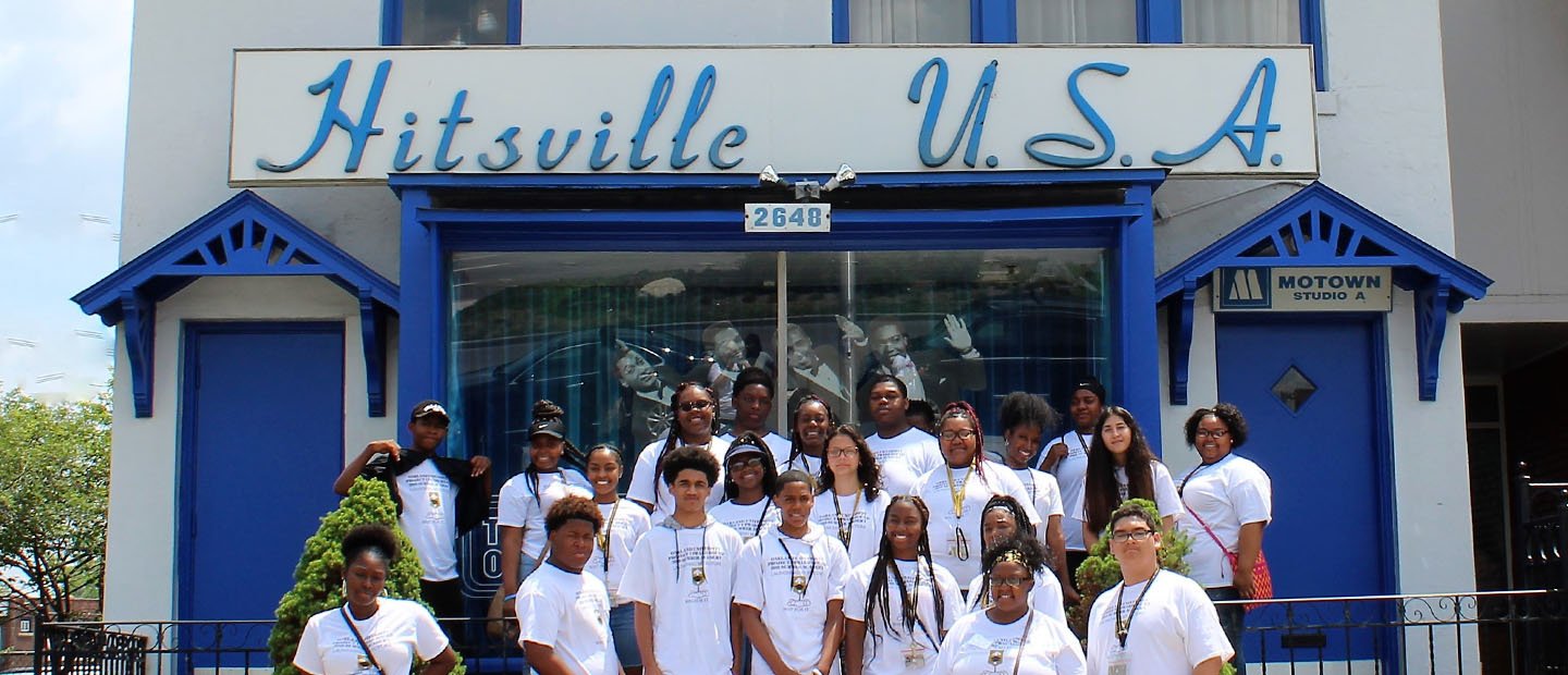 Enrichment A group of students posing for a photo outside of a Motown building with a sign that says "Hitsville U.S.A."