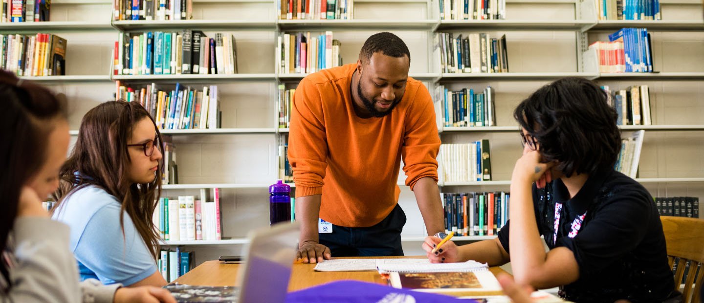 Four people studying at a table in a library.