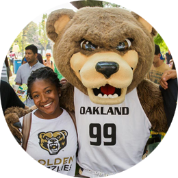 Female student wearing an O U shirt posing with The Grizz at Grizzfest