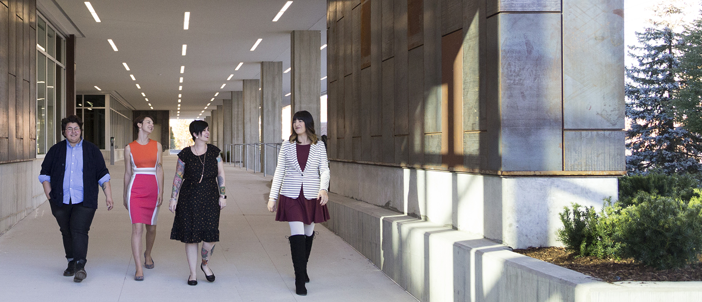 four women walking down a corridor outdoors