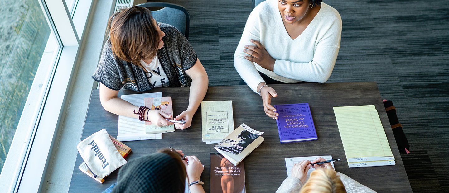 LGBTQ Minor aerial photo of four people seated at a table with books and notepads