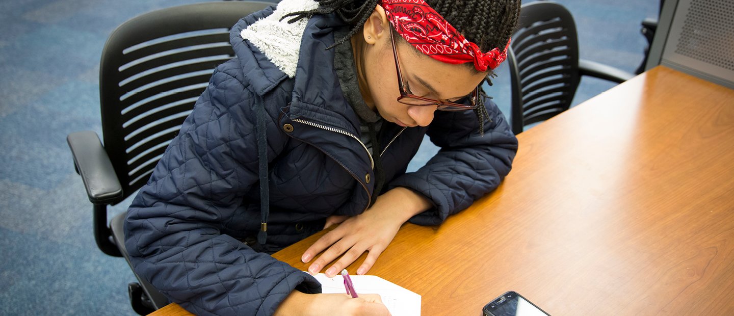 A student at a table, writing.