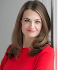 Laura Klein in a red dress leaning on a white wall.