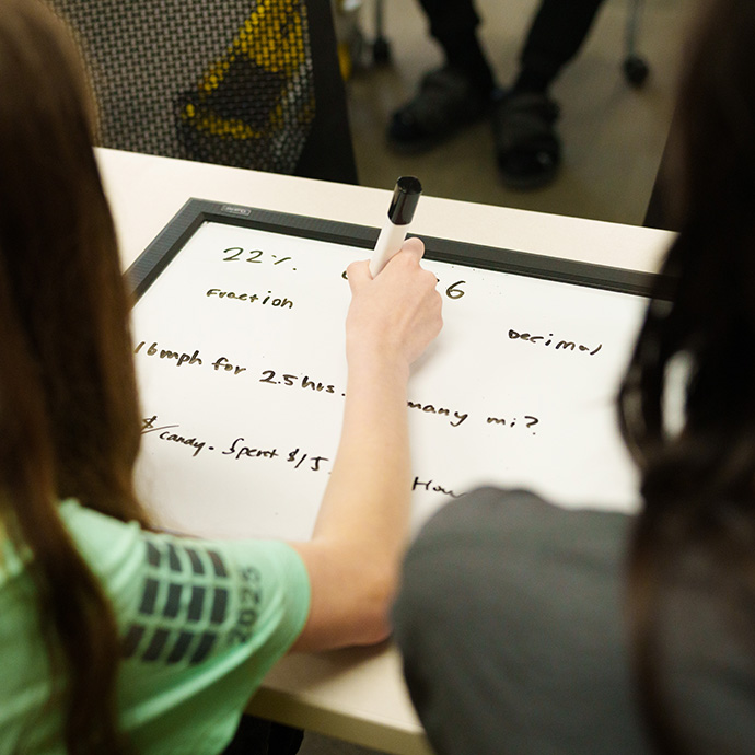 Person writing equations on white board