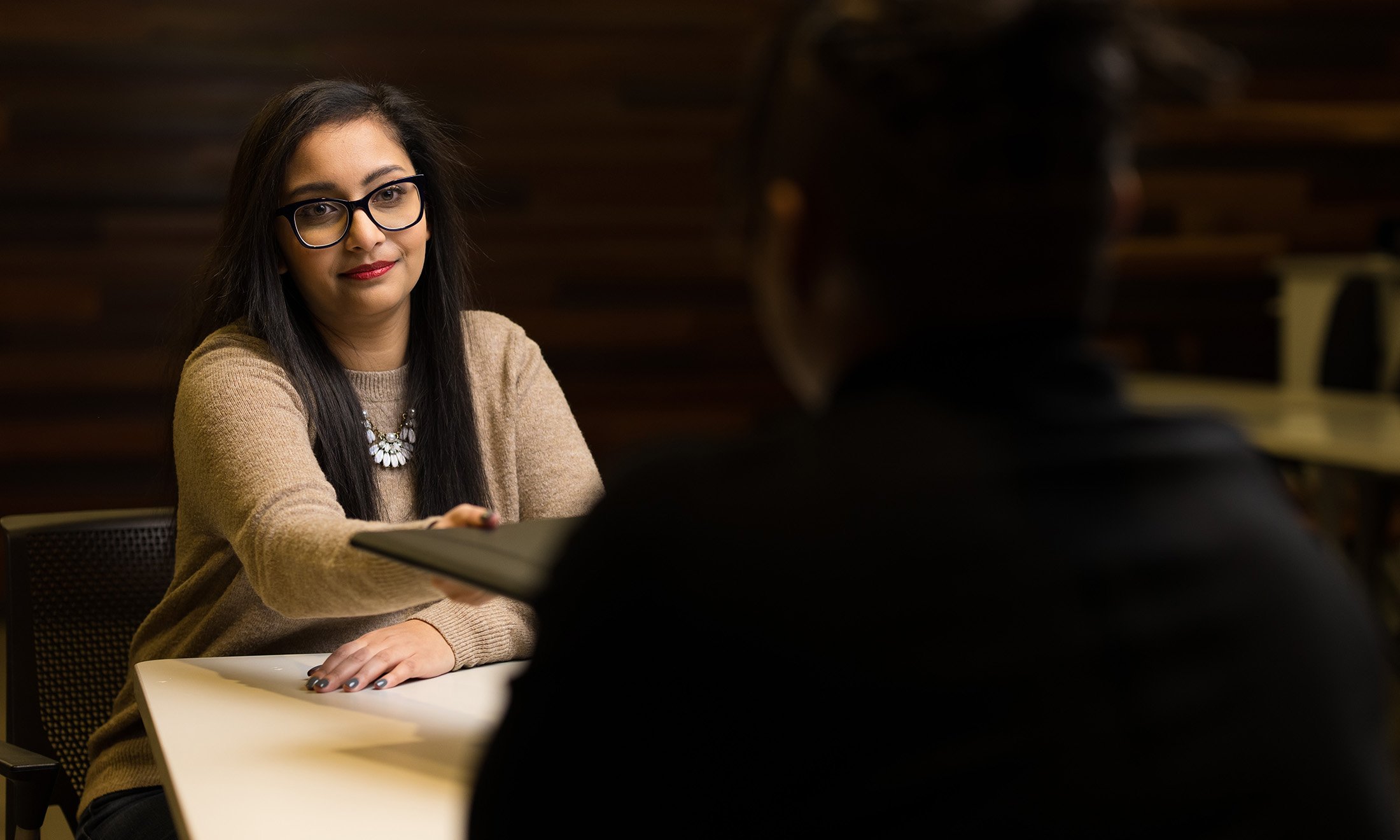 A person handing over a folder at a table