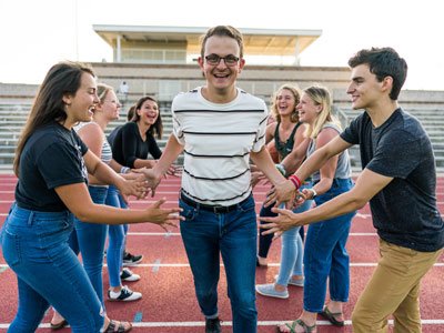 Man running through two rows of students with outstretched arms.
