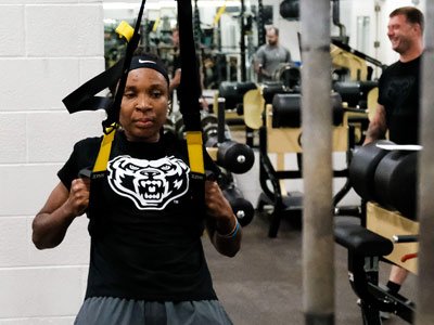 Woman in a gym using a suspension training device.