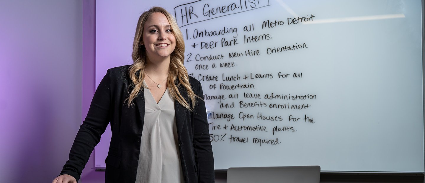 A young woman standing in front of a white board with 