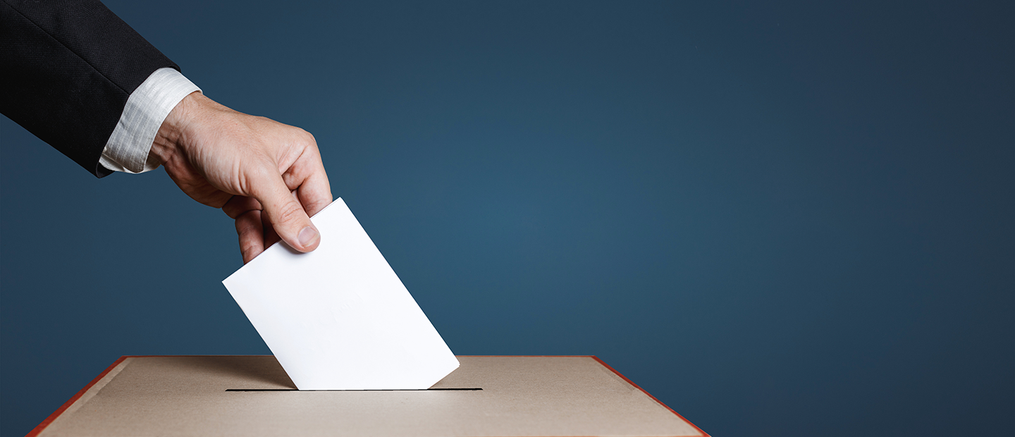 Closeup of hand putting ballot in a ballot box