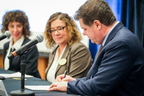 Easterseals MORC and OU representatives signing documents at a table with microphones