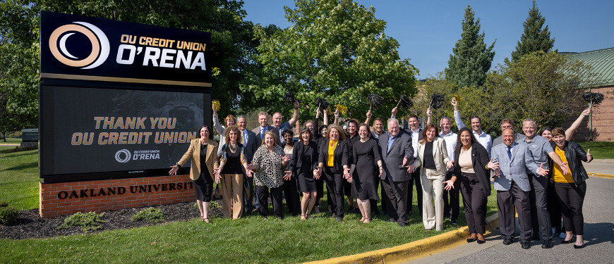 A large group of people posing near the OU Credit Union O'Rena marquee sign
