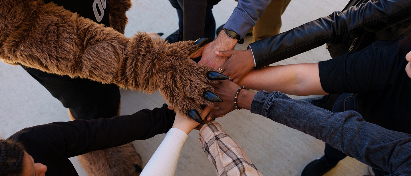 Hands and the Grizz mascot paw coming together in a circle