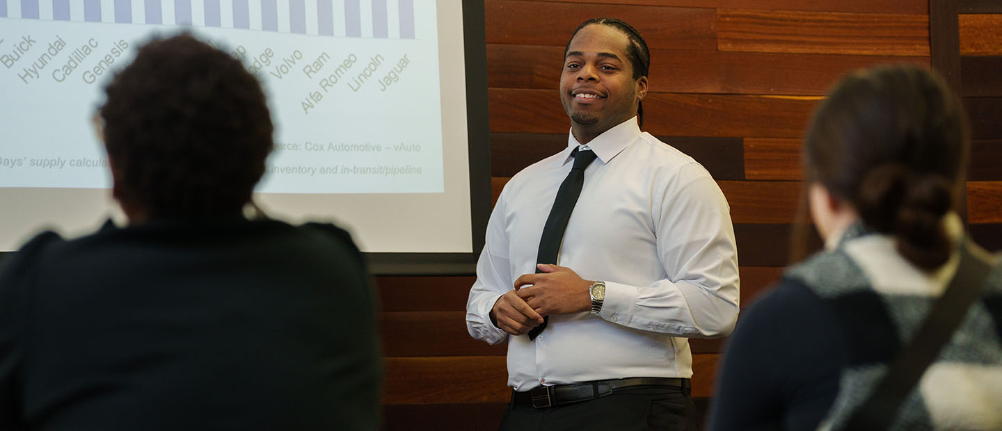 Alum Daviion Burks presenting in front of a screen.