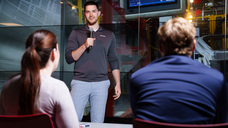Garrett Gilstorff holding a microphone, presenting to a group
